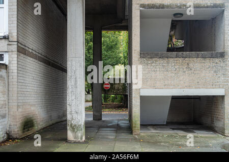A passageway between brick walls with concrete columns supporting structure above. Stock Photo