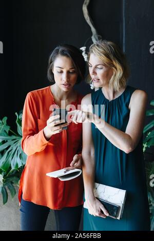 Businesswomen reading message on cellular phone Stock Photo