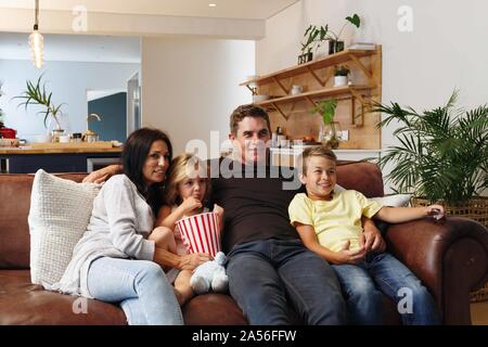 Parents and children relaxing with popcorn on sofa at home Stock Photo
