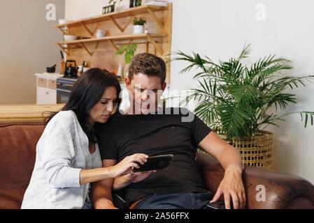 Couple reading text message on mobile phone at home Stock Photo
