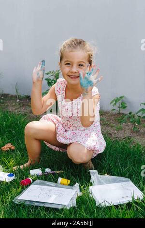 Happy little girl playing with paint in garden Stock Photo