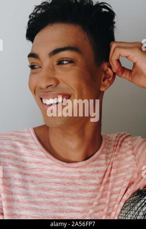 Happy young man with hand on ear looking away, head and shoulders Stock Photo