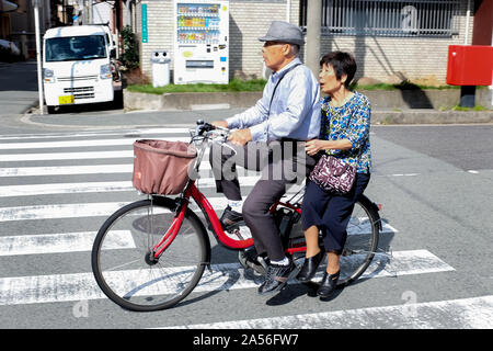 An elderly couple riding a bicycle in Osaka, Japan. Stock Photo