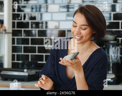 Businesswoman using cellular phone in pantry Stock Photo