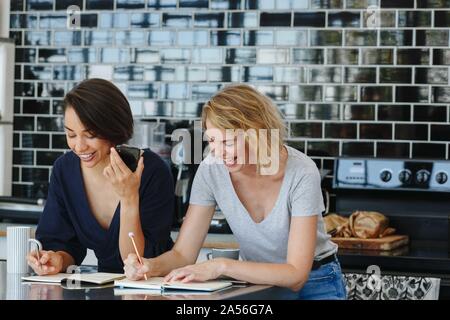 Colleagues talking and working at coffee break in pantry Stock Photo