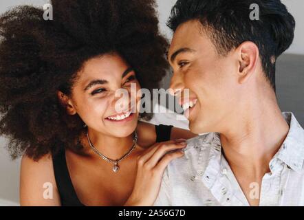 Happy young woman and boyfriend looking at each other in bedroom Stock Photo