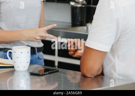 Colleagues playing rock-paper-scissors at coffee break in pantry Stock Photo