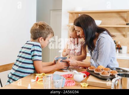 Mother and children baking cupcakes in kitchen Stock Photo