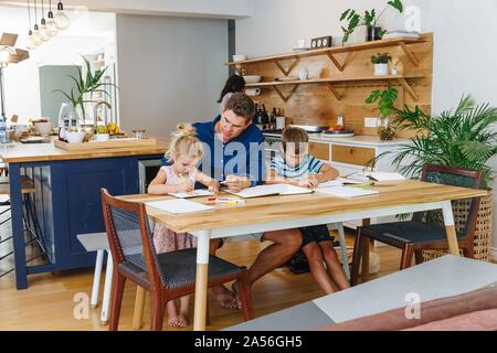 Father helping children with homework at home Stock Photo
