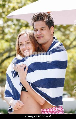 Couple wrapped in striped towel enjoying sun Stock Photo
