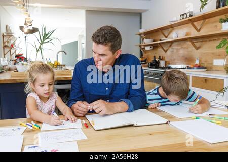 Father helping children with homework at home Stock Photo