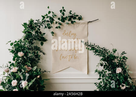 Romantic message on textile, hanging from floral foliage decoration at wedding reception Stock Photo