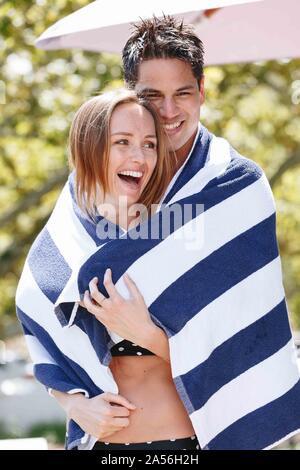 Couple wrapped in striped towel enjoying sun Stock Photo