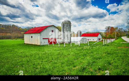 Red roof barn and silo along a country road. Stock Photo