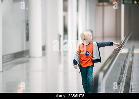 Boy with hand on handrail of moving walkway in airport, selective focus Stock Photo