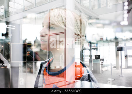 Blond haired boy gazing through window in airport, head and shoulders Stock Photo