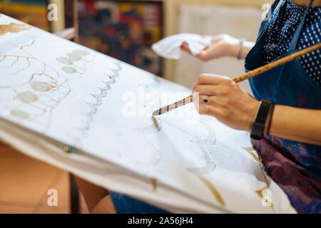 Young woman practicing Batik in art classroom, a traditional form of Indonesian painting, cropped view of hands Stock Photo