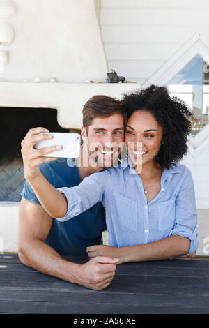 Couple taking selfie in beach house Stock Photo