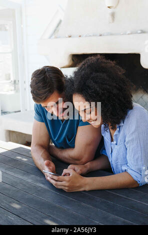 Couple using smartphone in beach house Stock Photo