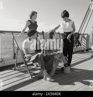 1960s, historical, four young adult passengers outside in the open-air on the wooden deck on board the Sagafjord cruise ship. Stock Photo