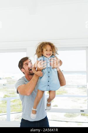 Father lifting daughter in mid air in beach house