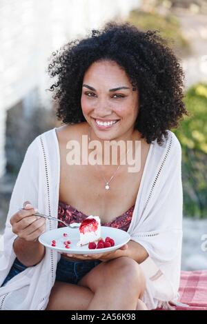 Woman holding plate of raspberry cake, smiling