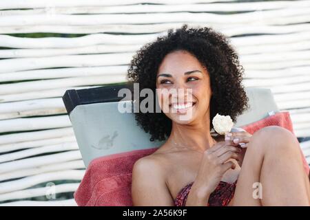 Woman enjoying ice cream on deckchair Stock Photo