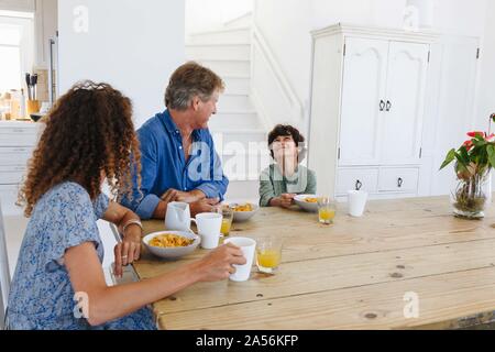 Parents watching son smile at breakfast at home Stock Photo