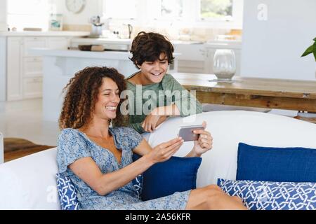 Mother and son smiling at text message on cellphone Stock Photo
