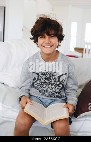 Boy reading book on sofa at home Stock Photo