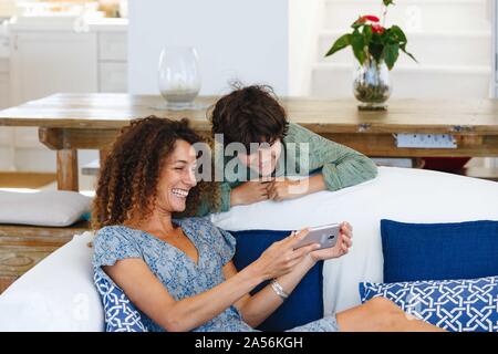 Mother and son smiling at text message on cellphone Stock Photo