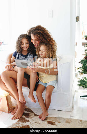 Mother and daughters using digital tablet at home Stock Photo