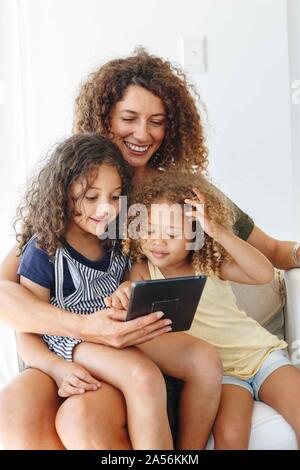 Mother and daughters using digital tablet at home Stock Photo