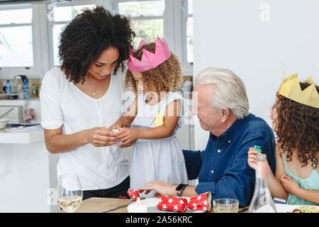 Woman teaching daughter fold paper flower at dining table Stock Photo