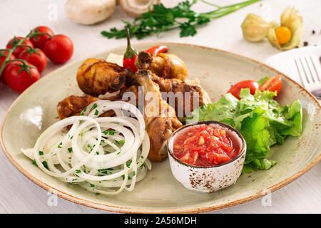 Fried chicken leg with tomato sauce and mixed salad in a serving dish. Copyspace. Stock Photo