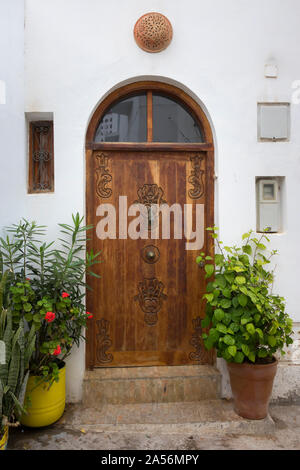 Old wooden decorated door with knocker in the shape of a hand in Asilah, Morocco Stock Photo