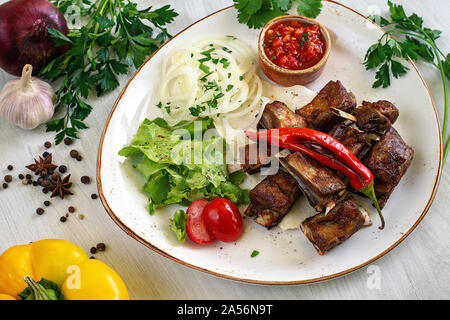 Lamb ribs on pita bread with salad and tomato sauce on a platter for serving. Copyspace. Stock Photo