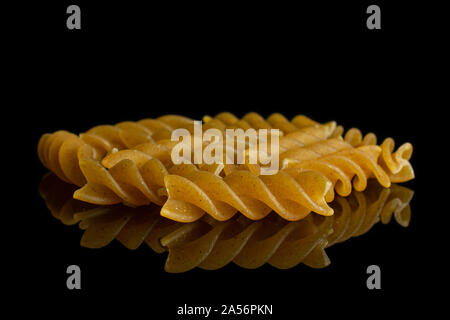 Lot of whole dry brown wholegrain fusilli isolated on black glass Stock Photo