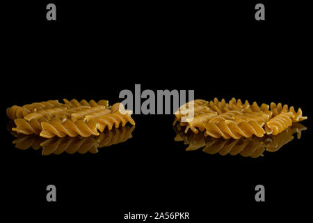 Lot of whole dry brown wholegrain fusilli isolated on black glass Stock Photo