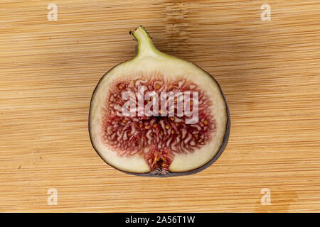 One half of sweet purple fig flatlay on light wood Stock Photo