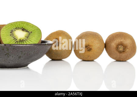 Group of three whole one half of exotic brown kiwi on glazed bowl isolated on white background Stock Photo
