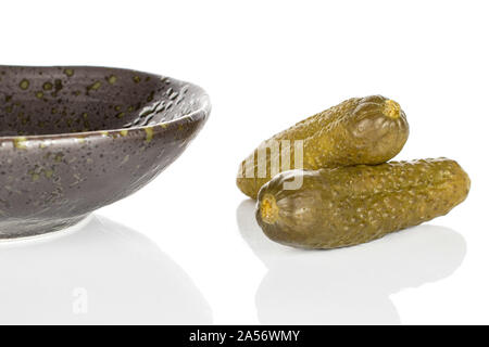 Group of two whole sour green pickle crossed on glazed bowl isolated on white background Stock Photo