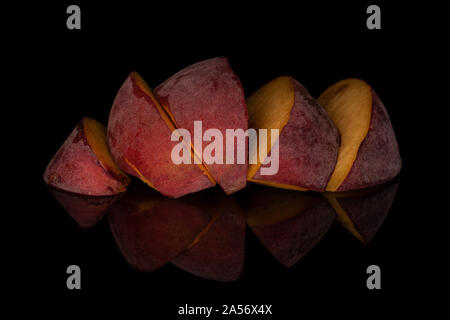Group of five slices of sweet red peach isolated on black glass Stock Photo