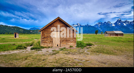 Storm clouds with outhouse, pumphouse and granary. Mormon Row, Grand Teton National Park. Stock Photo