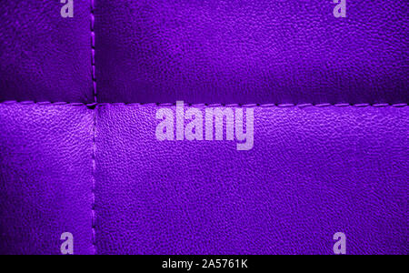 Bright shiny artificial textured leather painted in purple and lilac blend and stitched with thread. Close-up of sofa surface. View from above. Detail Stock Photo