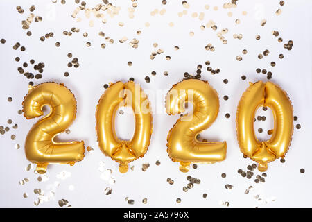 Aluminum balloons in the form of numbers 2020 with golden confetti. New Year's celebration. Golden Globes. Christmas party decoration. Stock Photo