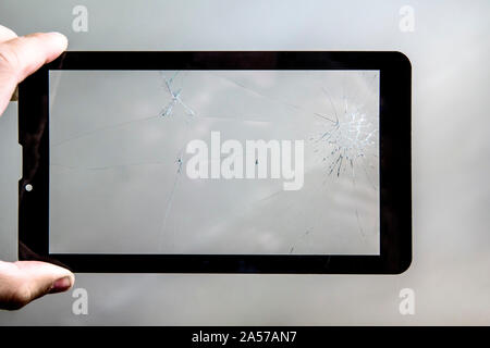 broken tablet screen. Cracks on the glass of the tablet computer in the hands of men. Stock Photo