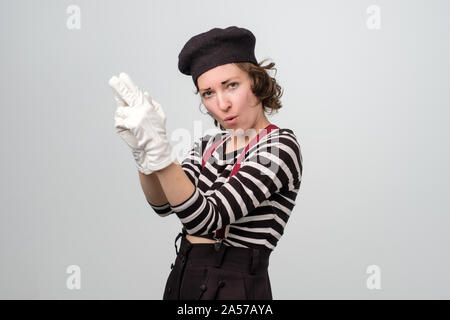 Mime woman is pointing with fingers like pistol, looking at camera and smiling. Stock Photo