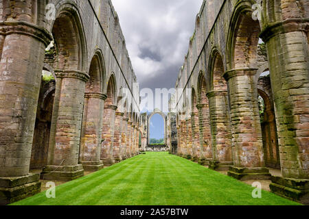 Colorful stone pillars in the nave of Fountains Abbey Cistercian monastery church ruins with green grass North Yorkshire England Stock Photo