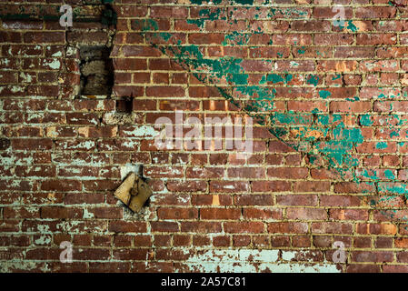 old damaged red brick wall with faded green paint background Stock Photo